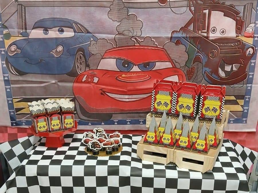 Mesa do tema Corrida na Comemorando Festas, com painel de carros, toalha quadriculada e caixinhas personalizadas
